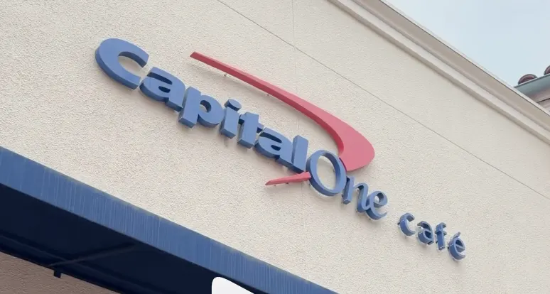 Capital One Café signage with blue dimensional lettering and red logo on a beige exterior wall.